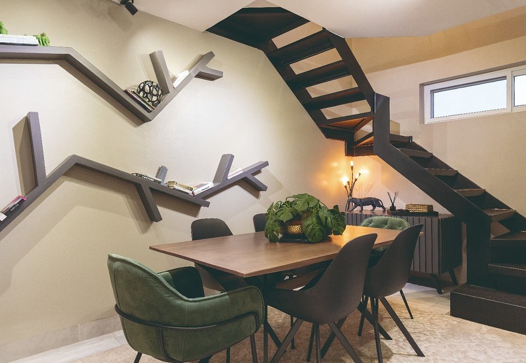 Modern dining area with unique angular shelving, black metal staircase, and natural decor.