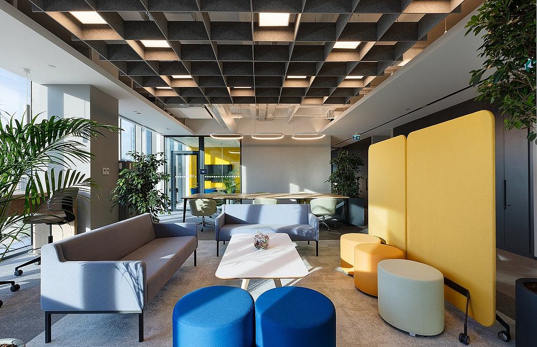 A modern, bright office space with a geometric ceiling, colorful furniture, and plants.