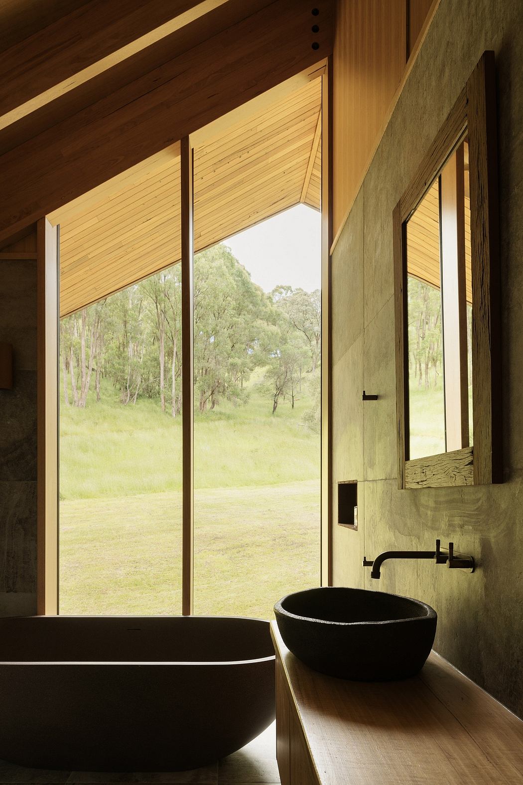 Rustic cabin interior with large windows overlooking a lush, forested landscape.