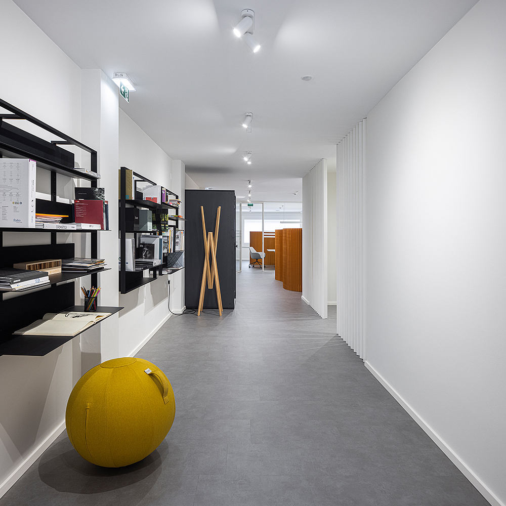 Modern office space with sleek shelving, minimalist decor, and a yellow accent piece.