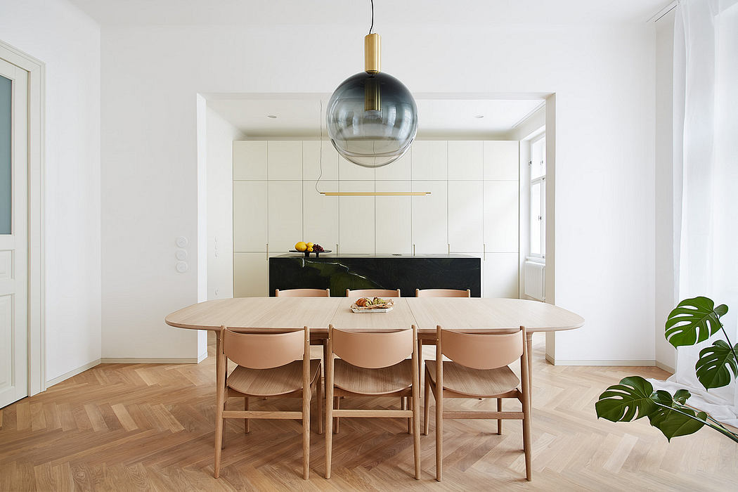 A modern, minimalist kitchen and dining space with neutral tones, sleek pendant light.