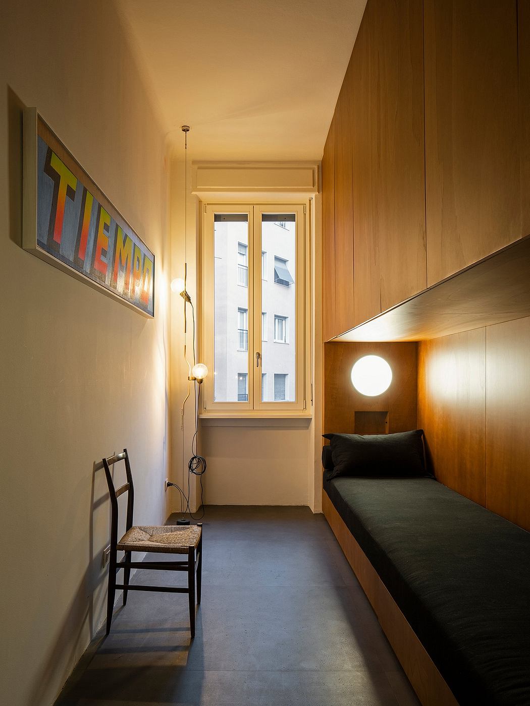 The interior features a wooden-paneled hallway with a colorful artwork, a chair, and lighting fixtures.