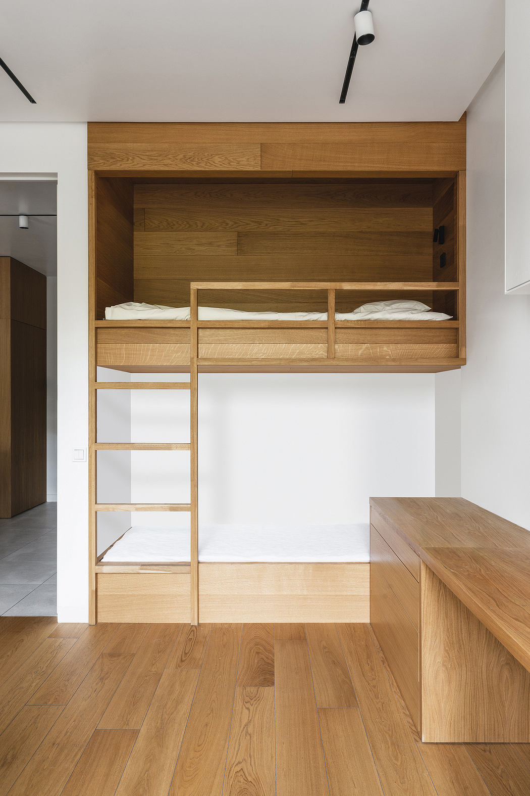 A cozy loft bed with wooden shelves and drawers, complemented by a sleek wooden desk.