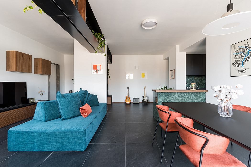 Modern open-plan living room with teal sofa, orange chairs, and wooden accents.