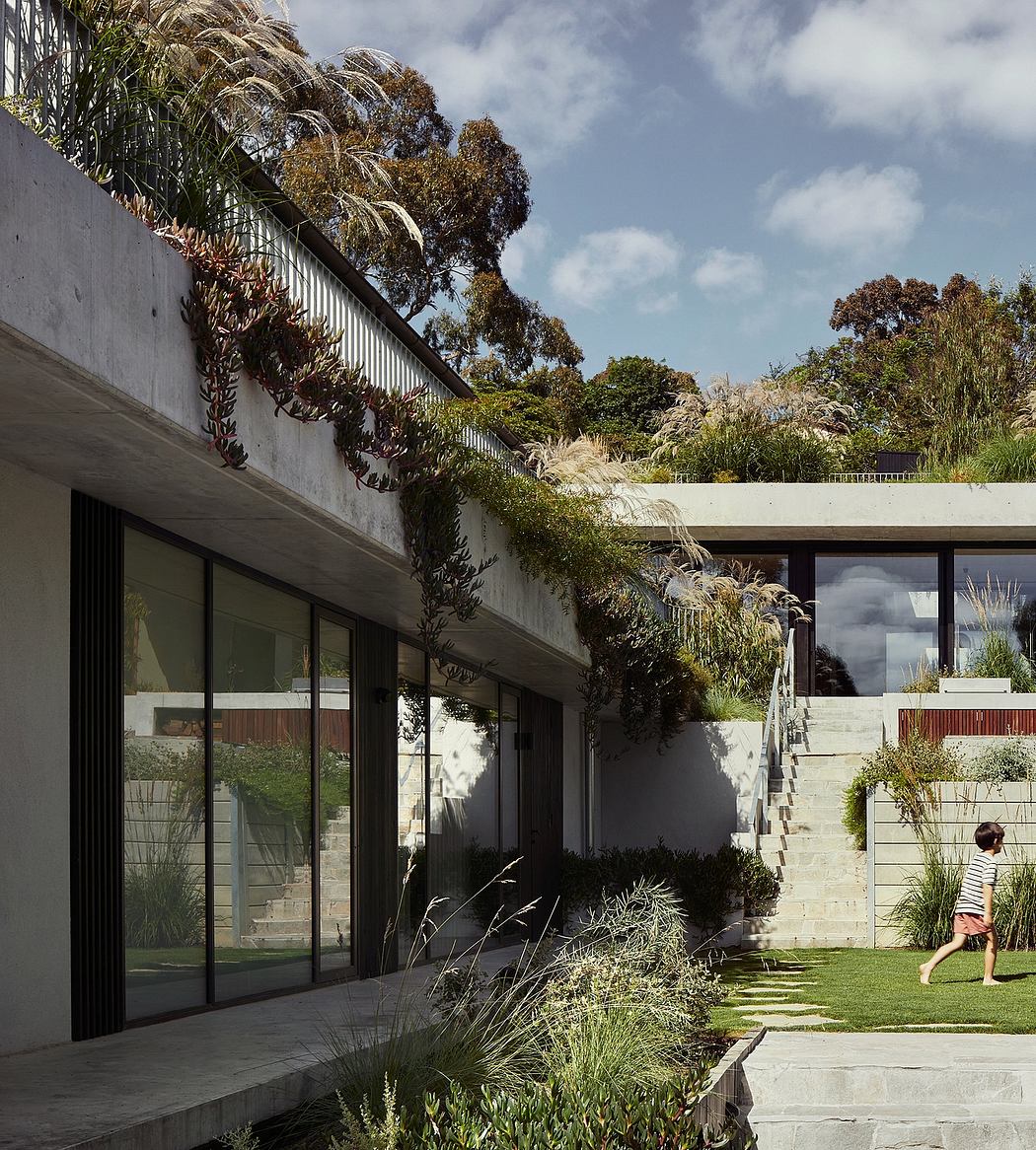 Striking modern architecture with lush tropical landscaping and a person walking on the path.