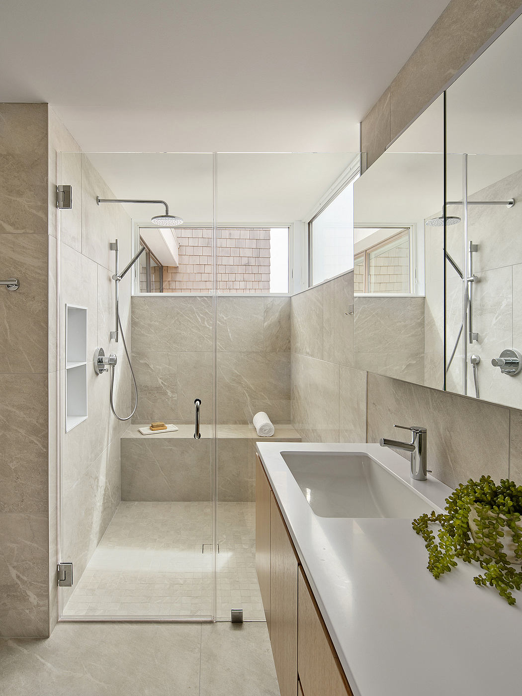 A contemporary bathroom with sleek glass shower enclosure, modern vanity, and natural stone tiles.
