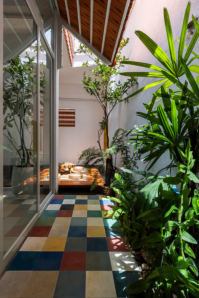 Vibrant interior with lush greenery, colorful tile flooring, and a cozy seating area.
