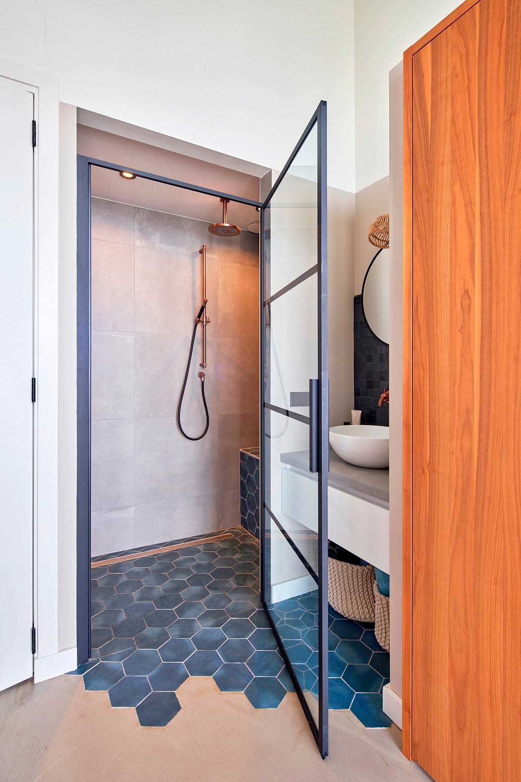 A modern bathroom with hexagonal tiles, glass shower enclosure, and wooden accents.