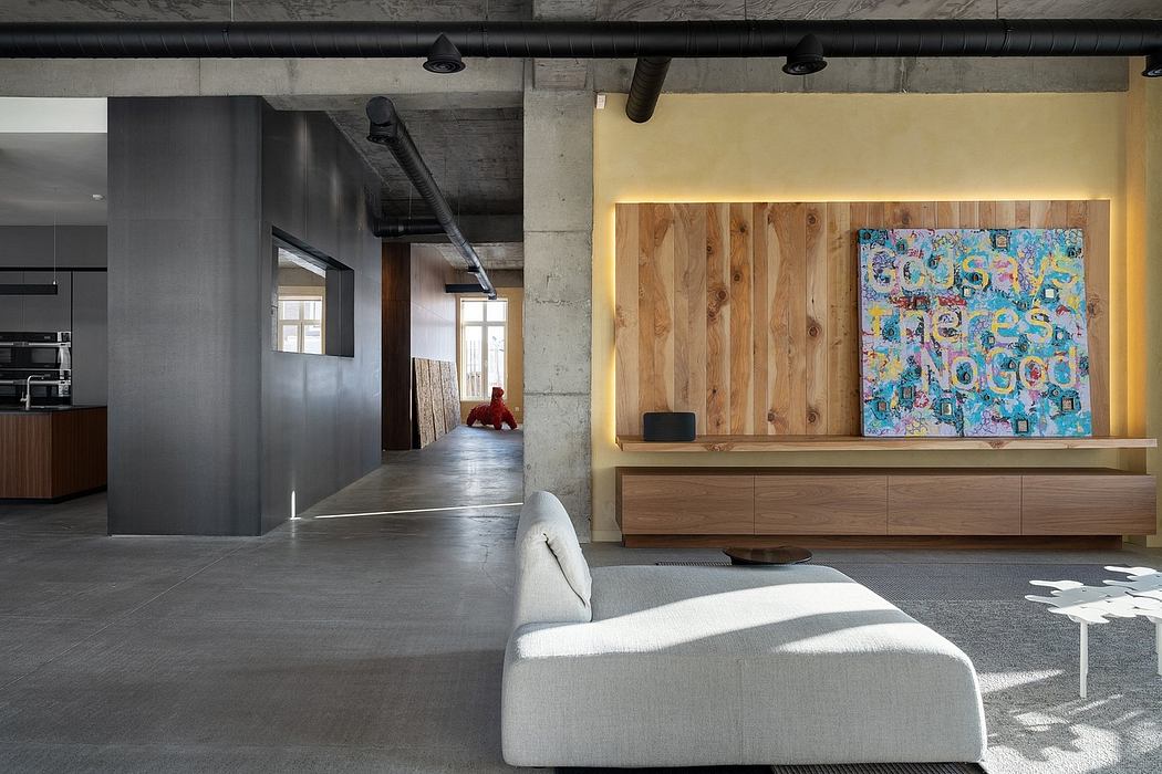 Spacious open-plan interior with industrial concrete elements, wooden accents, and vibrant artwork.