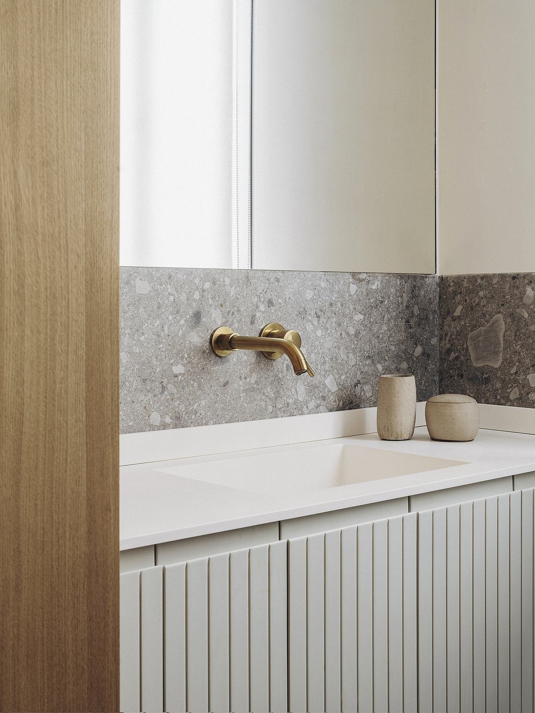 Minimalist bathroom design with marble backsplash, brass fixtures, and simple vanity.