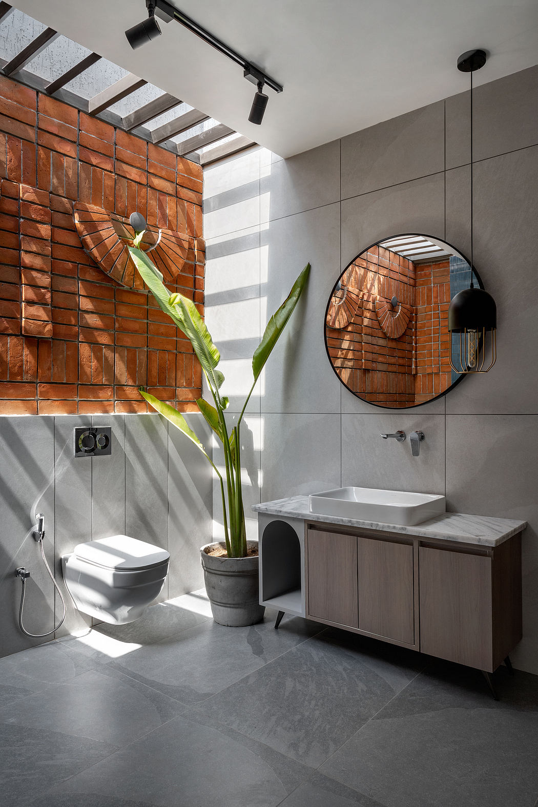 A modern bathroom with exposed brick walls, sleek fixtures, and a large circular mirror.