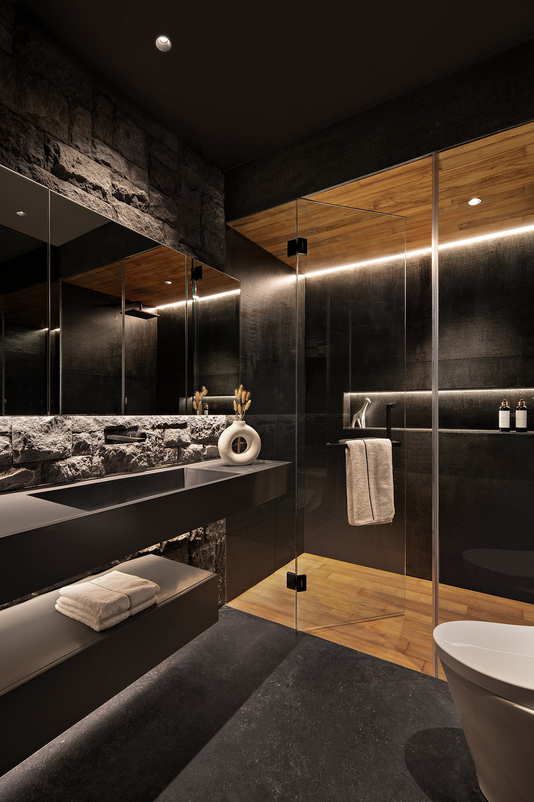 A dark, modern bathroom with stone walls, wooden vanity, and glass shower enclosure.