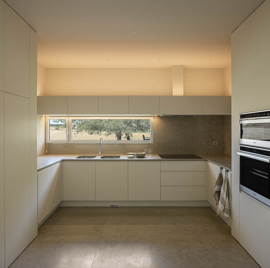 Minimalist kitchen with floor-to-ceiling cabinets, sleek countertops, and large window.