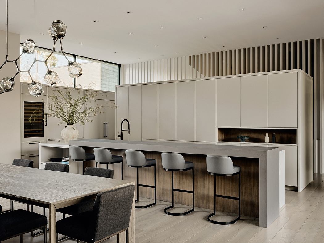 Sleek, modern kitchen with minimalist cabinetry, pendant lighting, and a wooden dining table.