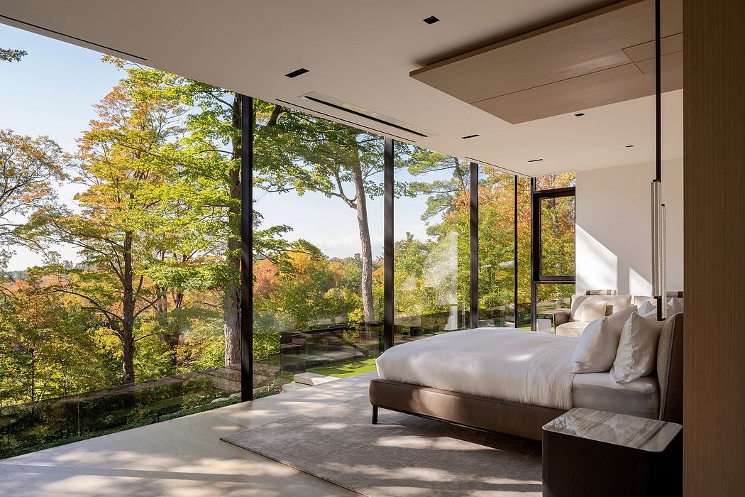 Panoramic glass walls frame a serene forest view, complemented by a minimalist bedroom design.