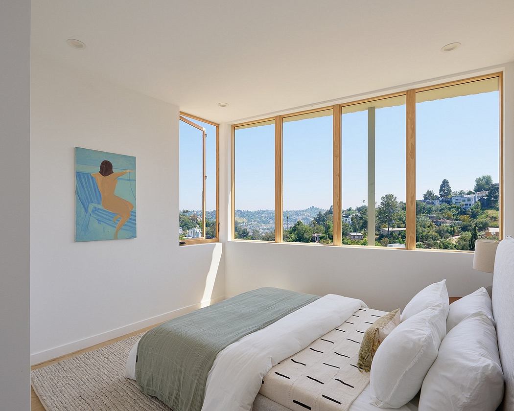Spacious bedroom with floor-to-ceiling windows offering panoramic city views and modern decor.