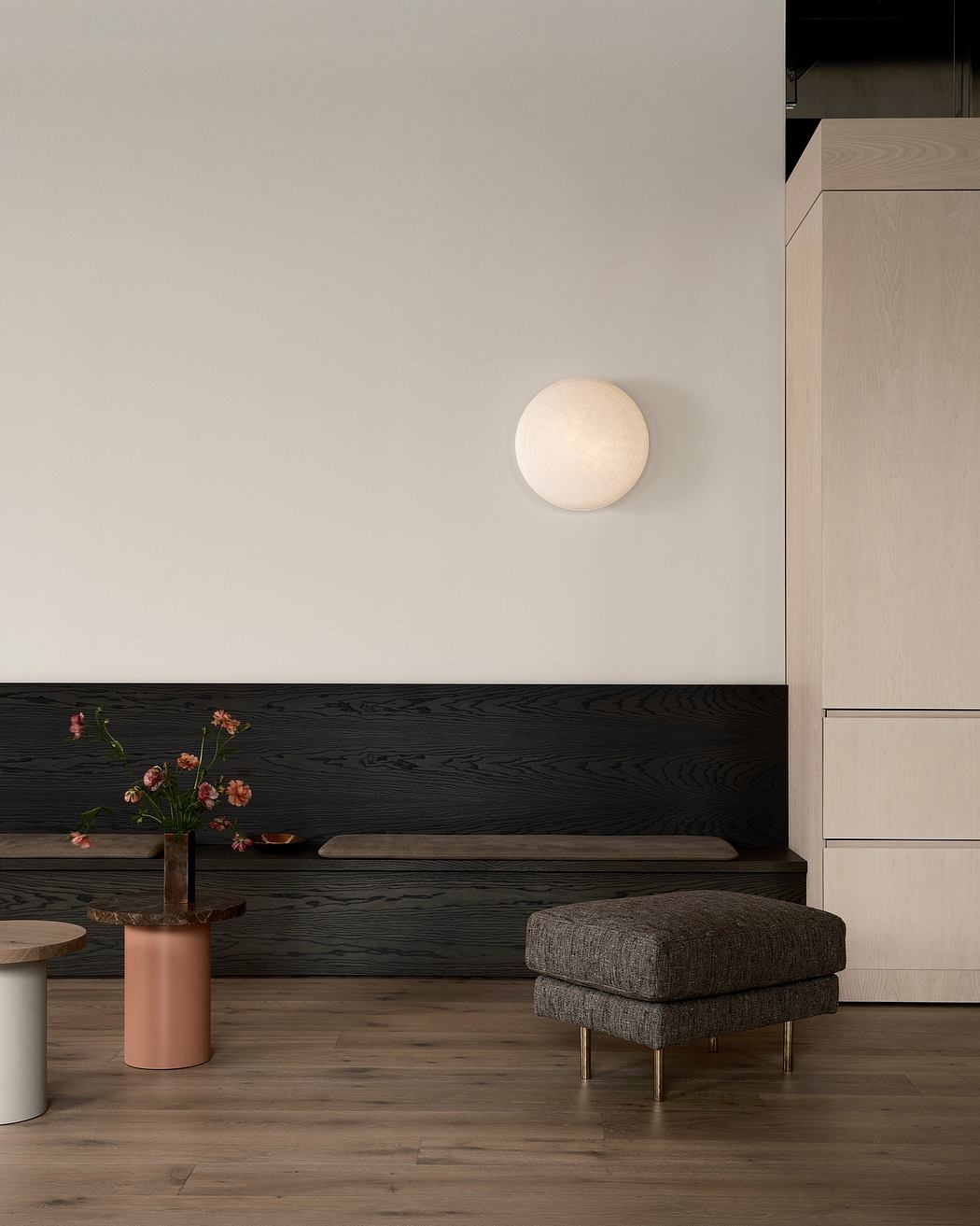 Minimalist living space with wooden accents, globe lighting fixture, and floral decor.