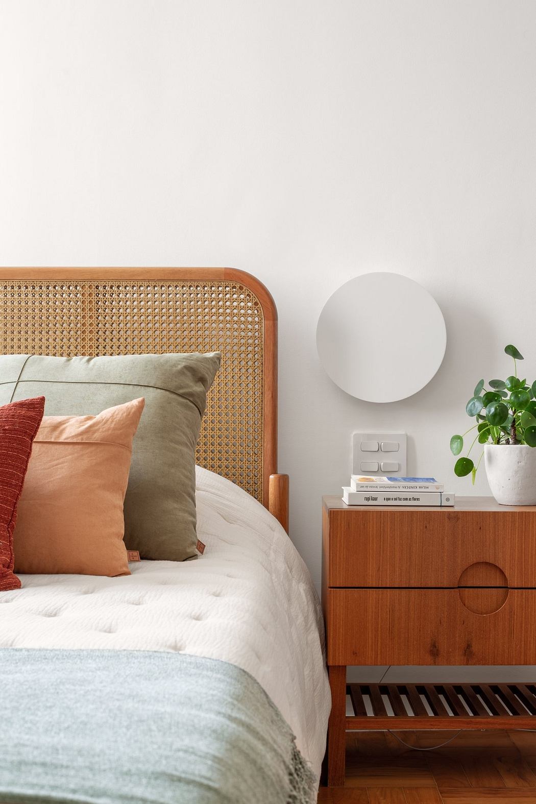 Cozy bedroom with cane headboard, neutral bedding, and minimalist nightstand decor.