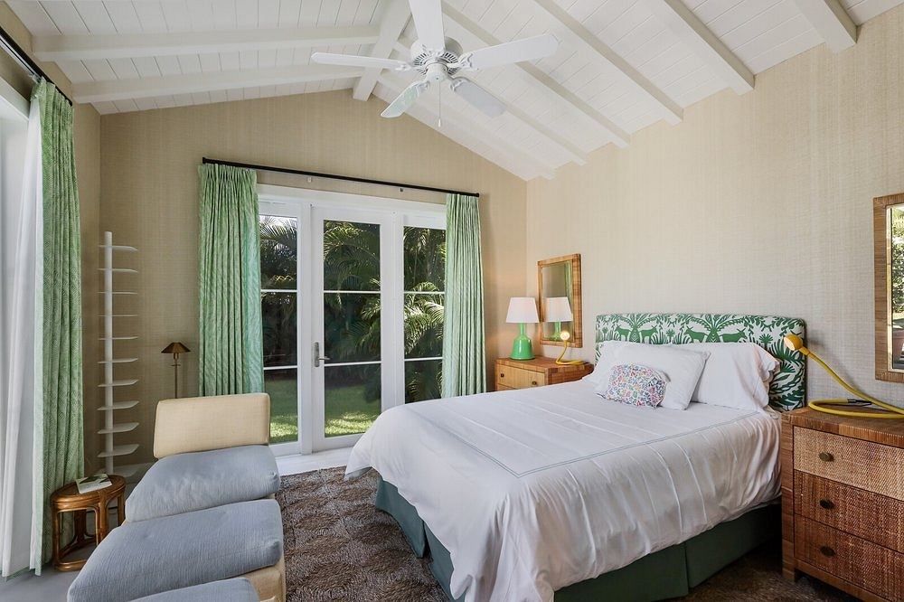 Bright, airy bedroom with vaulted ceilings, wood accents, and French doors leading outside.