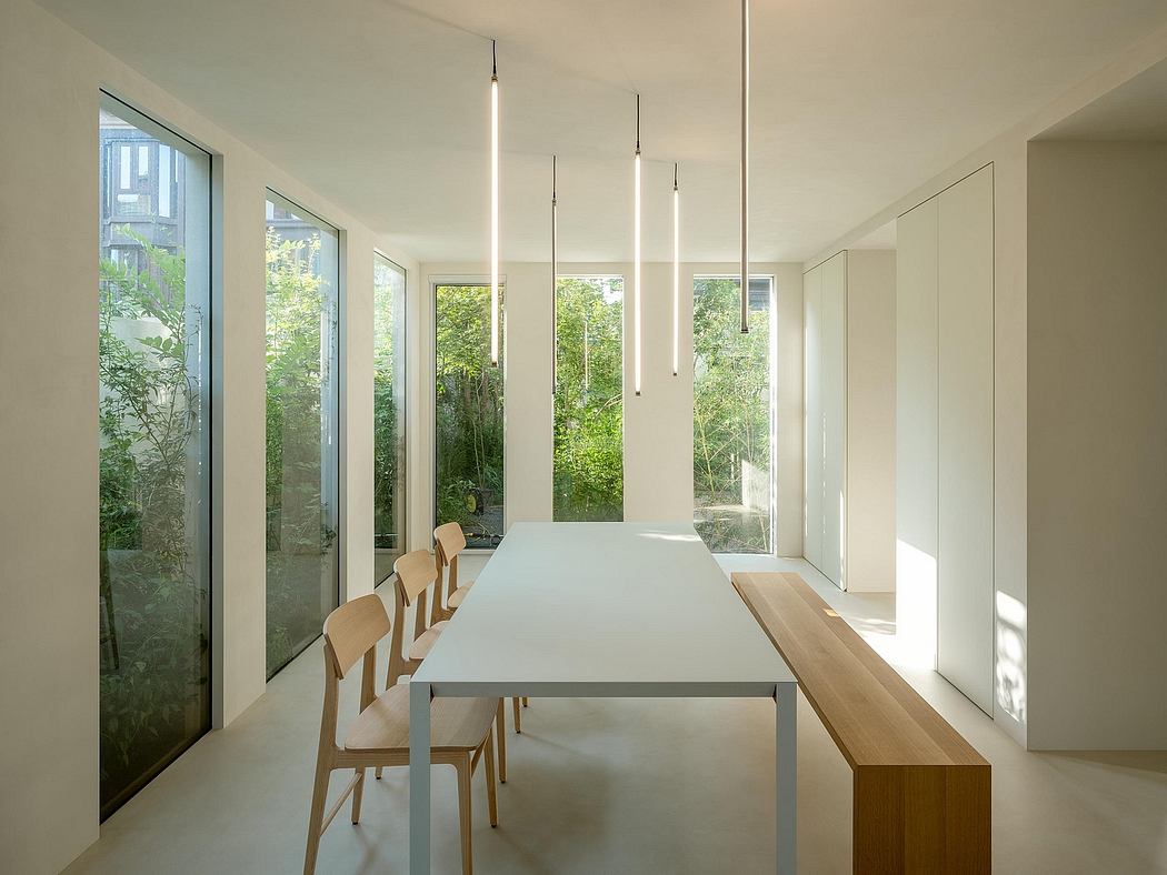 Minimalist dining area with floor-to-ceiling windows, sleek table, and modern lighting.