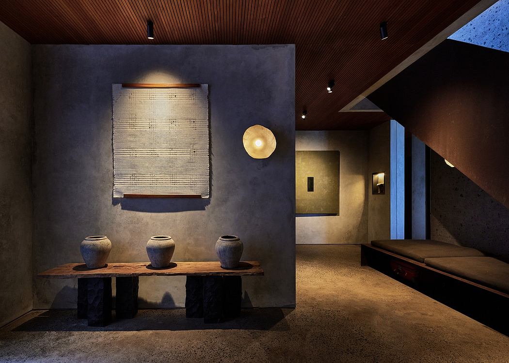 Warm-toned modern interior with wooden ceiling, concrete walls, and decorative pottery.
