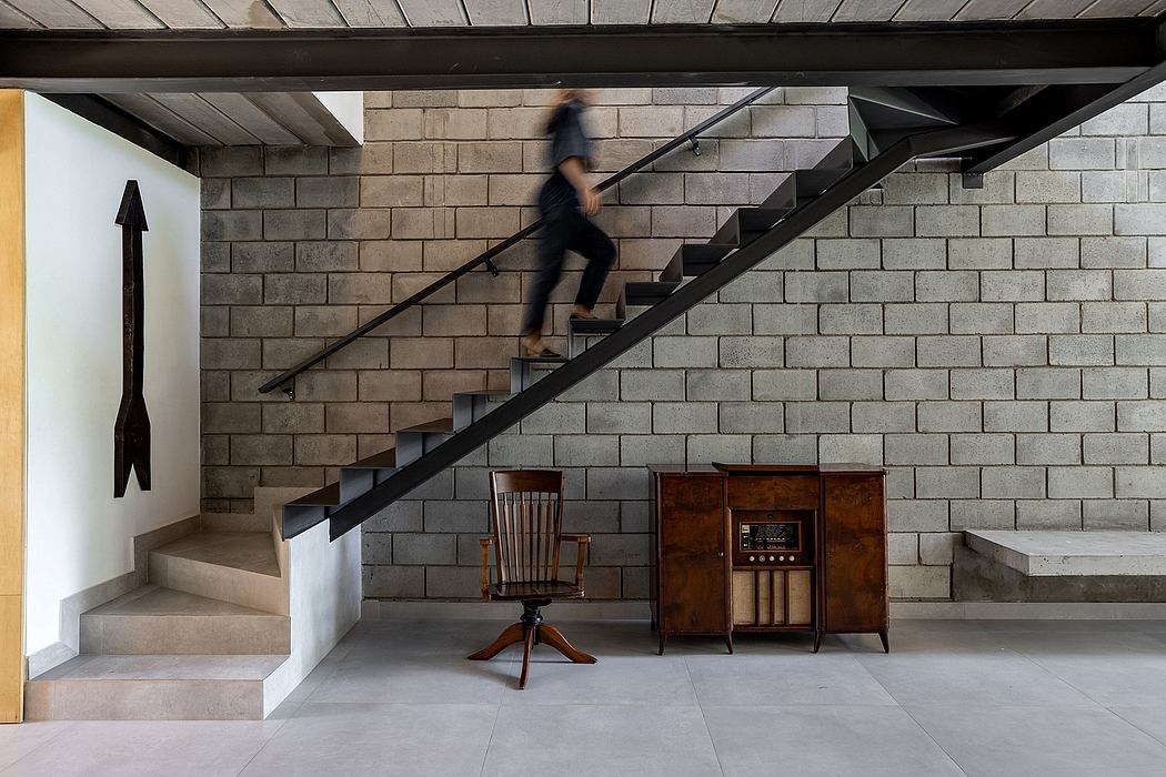 A modern, minimalist staircase with a brick wall, vintage furniture, and an industrial vibe.