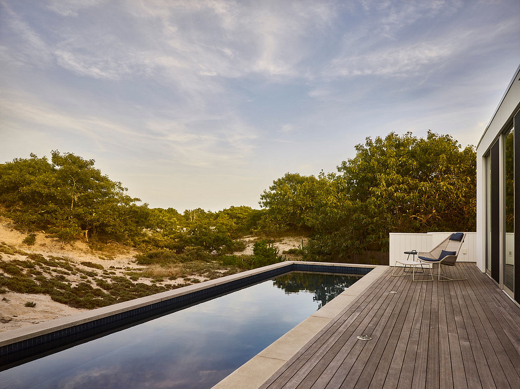 Outdoor pool with wooden deck overlooking lush, verdant landscape under cloudy sky.