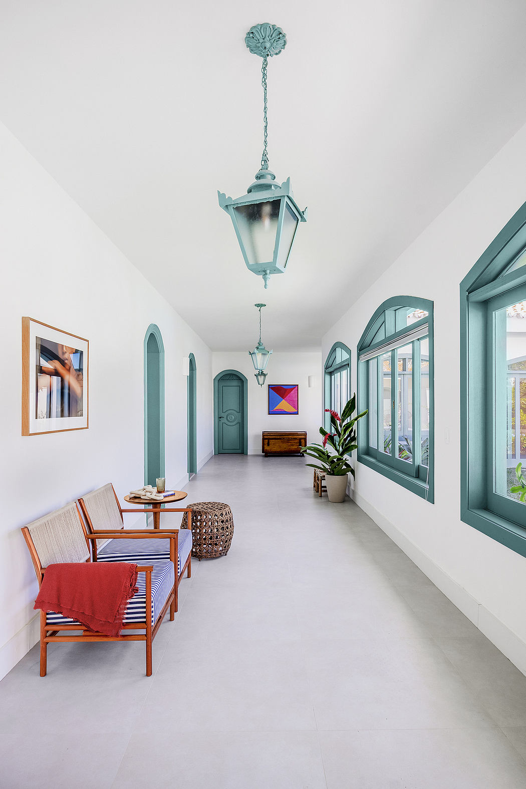 Elegant hallway with arched doorways, teal fixtures, and a mix of modern and vintage furnishings.
