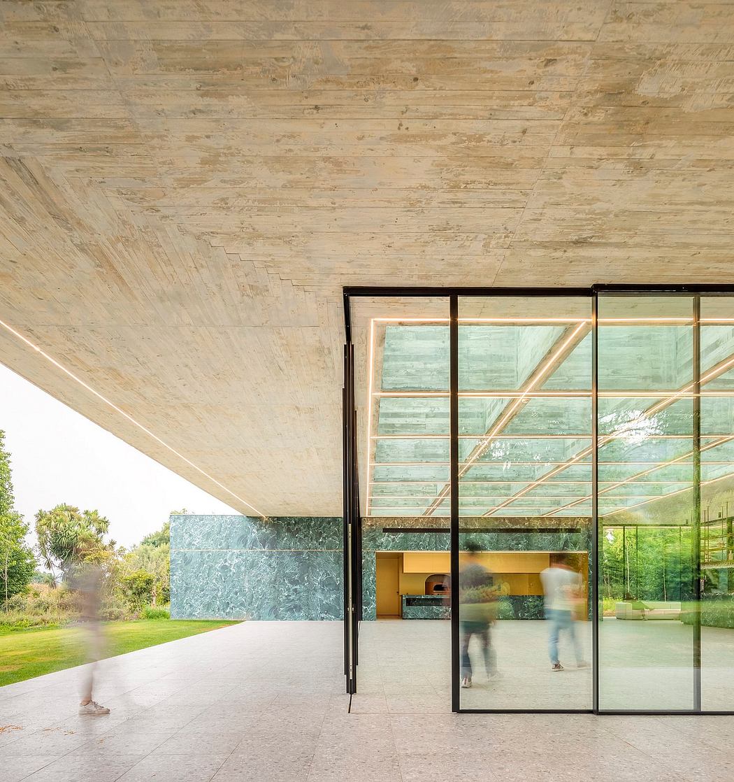 Minimalist architecture with expansive glass walls, concrete ceiling, and stone detailing.