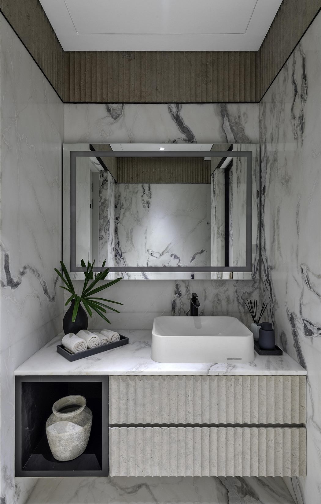 Modern bathroom with marble walls, integrated vanity, and sleek mirror frame.