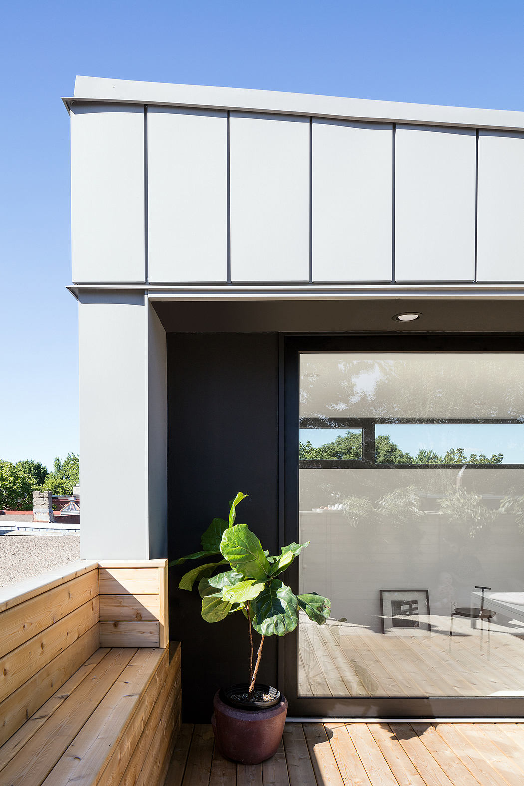 Modern building with clean lines, large windows, and a potted plant on the wooden deck.