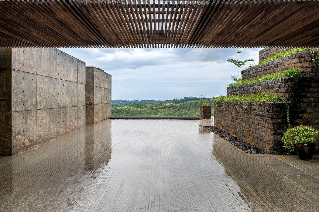 Expansive, minimalist outdoor patio with concrete walls, wooden deck, and lush vegetation.