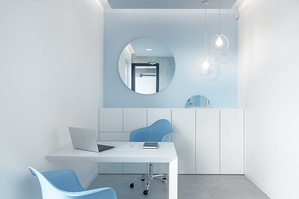 Minimalist home office with white furniture, circular mirrors, and pendant lighting.