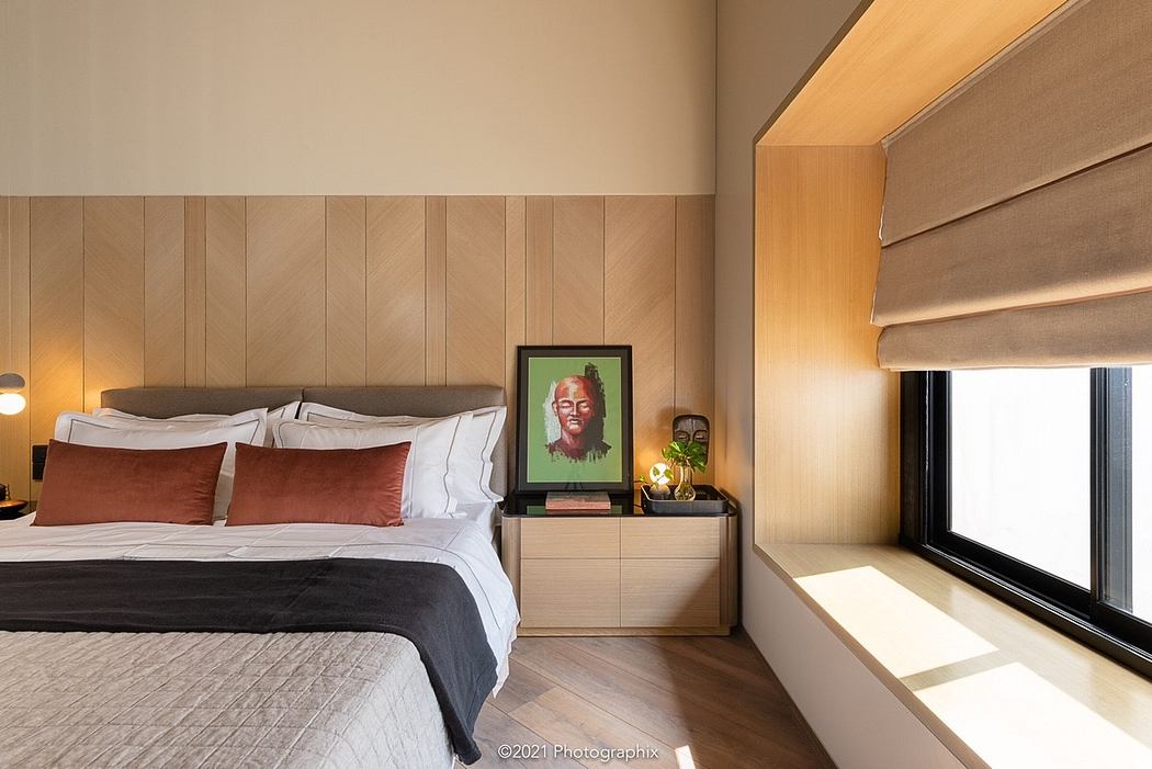 Cozy bedroom with warm wood paneling, minimalist furnishings, and vibrant artwork.