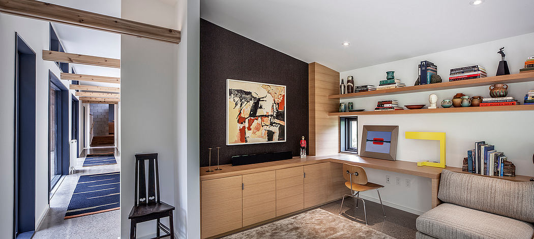 Modern open-plan living space with wooden cabinetry, shelves, and abstract artwork.