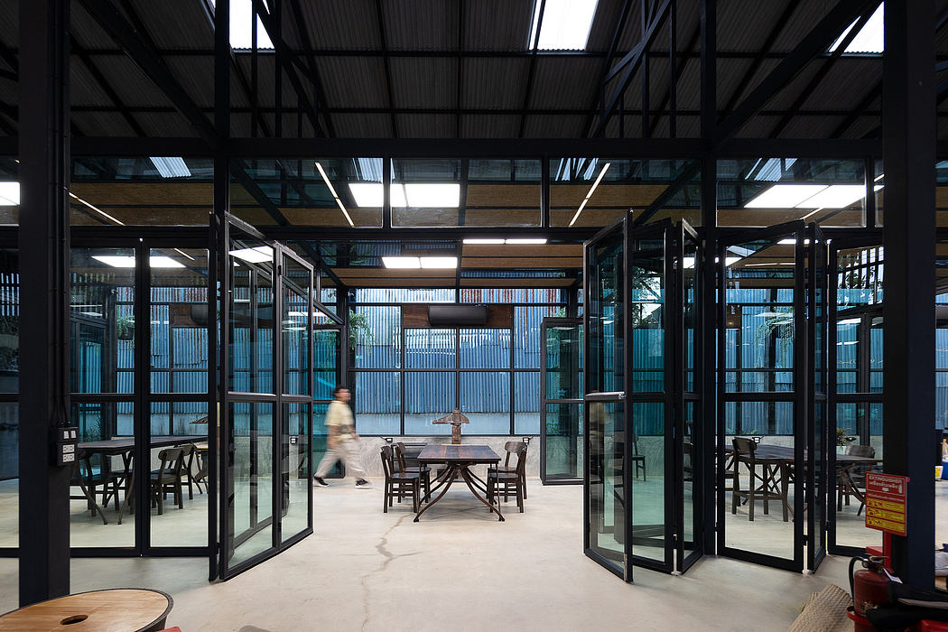 Modern industrial-style cafe interior with glass walls, metal beams, and concrete flooring.