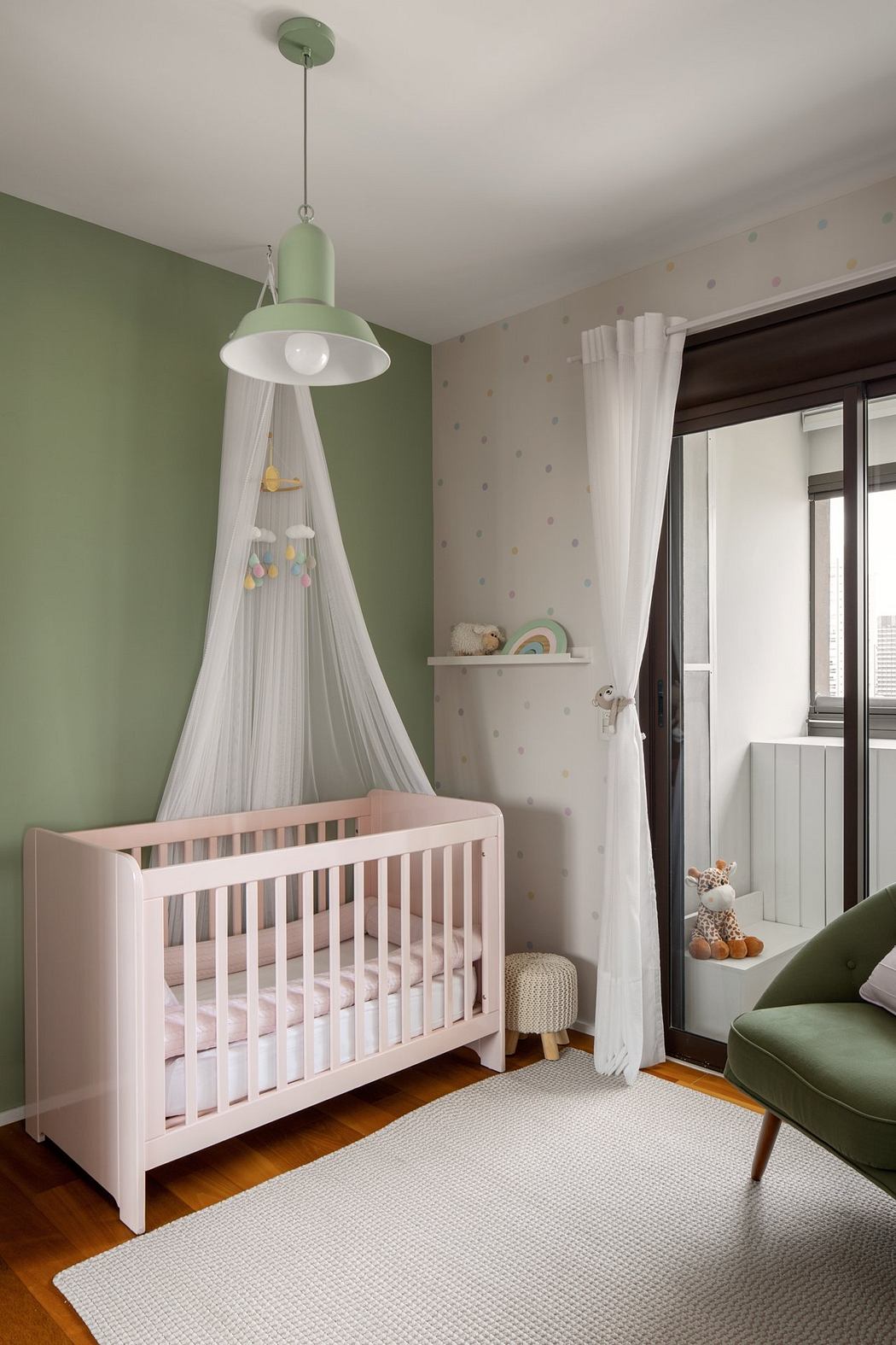 A cozy nursery with a white crib, green and white polka dot walls, and a pendant light.