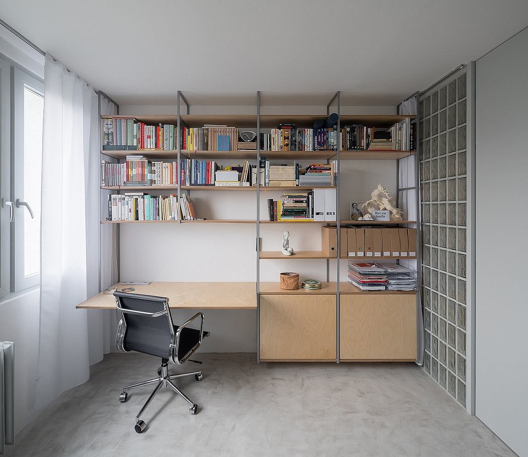 Minimalist home office with ample shelving, desk, and concrete flooring. Sleek, functional design.