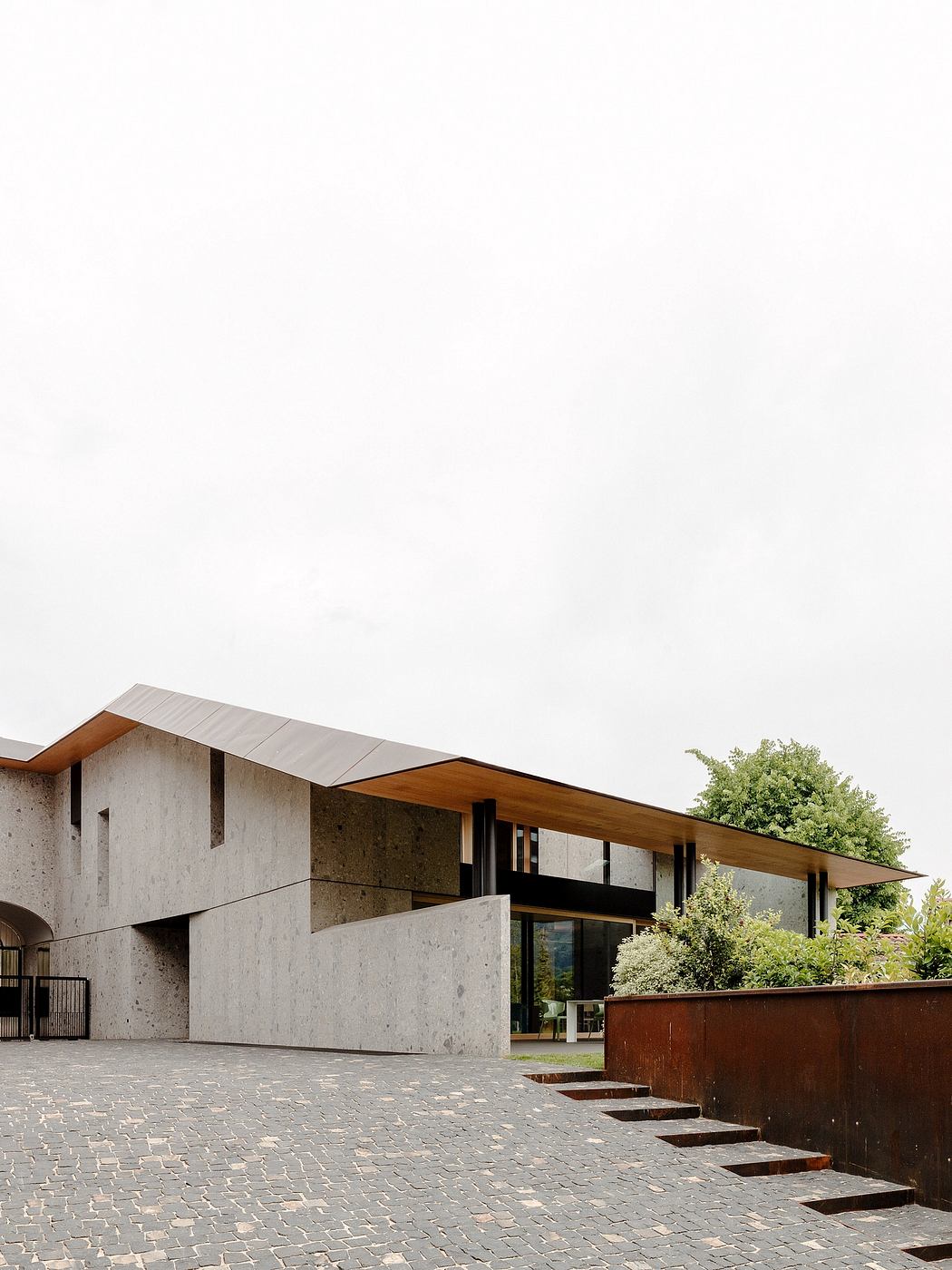A modern, angular building with a wooden roof overhang and concrete facade.
