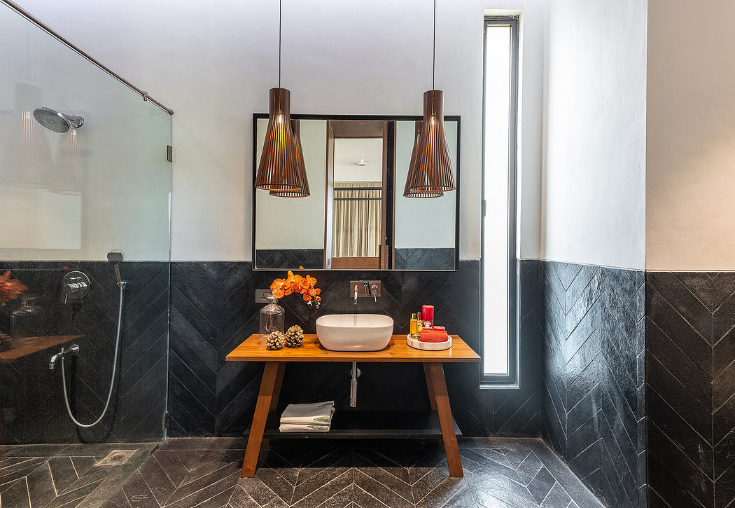 Sleek, modern bathroom with rich wood vanity, stylish pendant lighting, and striking black tile.