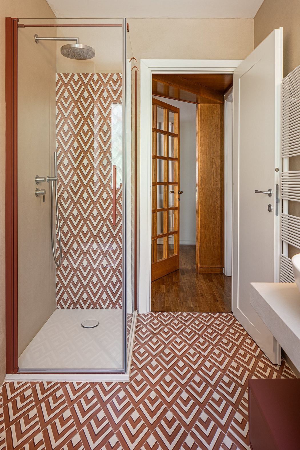 A modern bathroom with a patterned tile floor and a glass-enclosed shower.