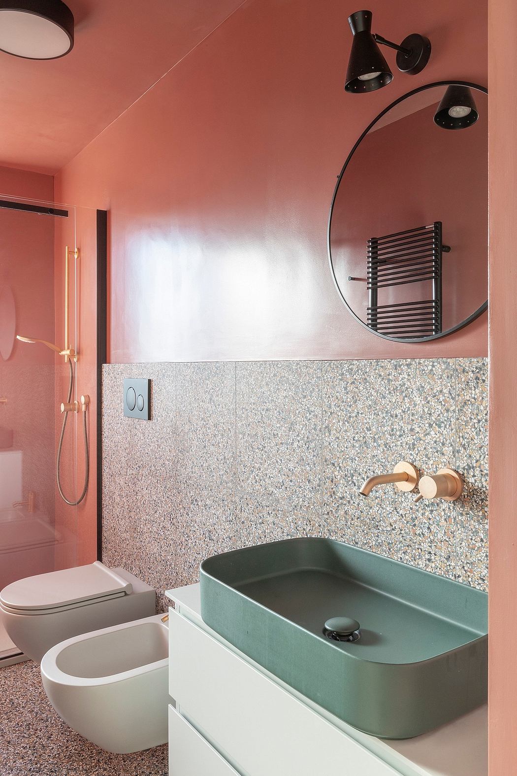 A modern bathroom with a mint green sink, black fixtures, and a terrazzo tile accent wall.