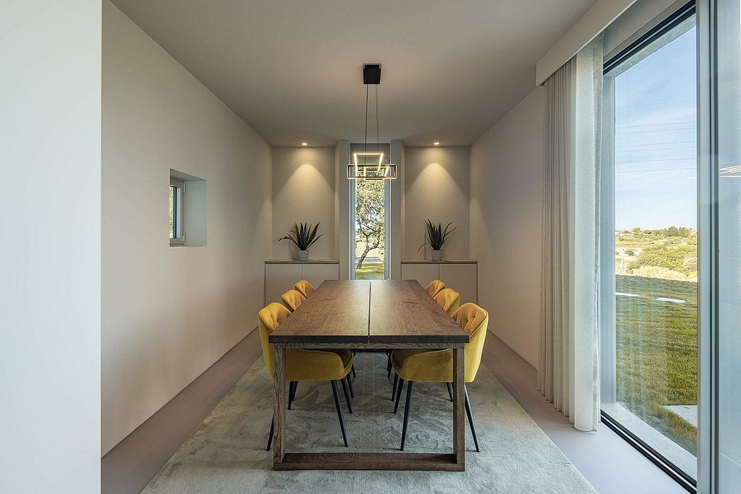Minimalist dining room with wooden table, yellow chairs, and large windows overlooking nature.