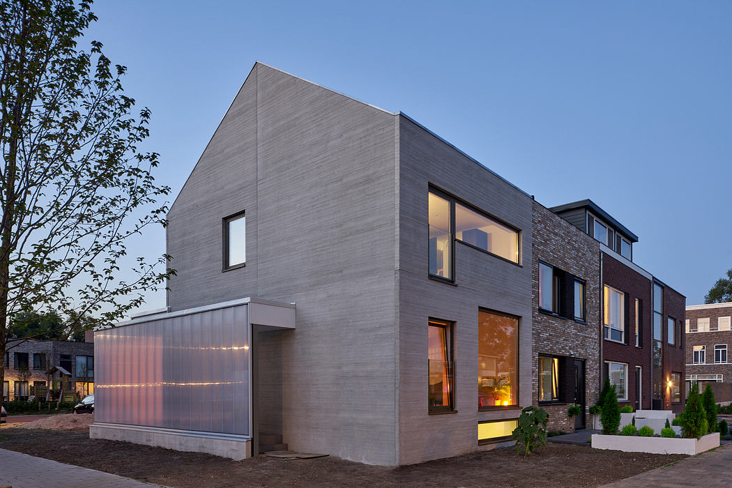 A modern, angular residential building with large windows and a garage door in the foreground.