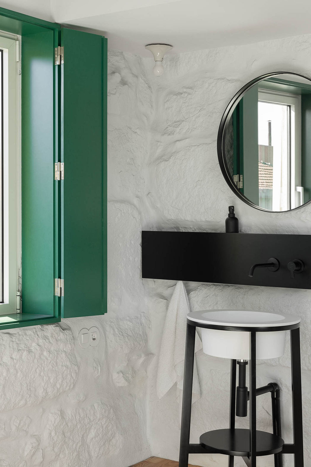 Minimalist bathroom with green cabinets, black vanity, and round mirror.