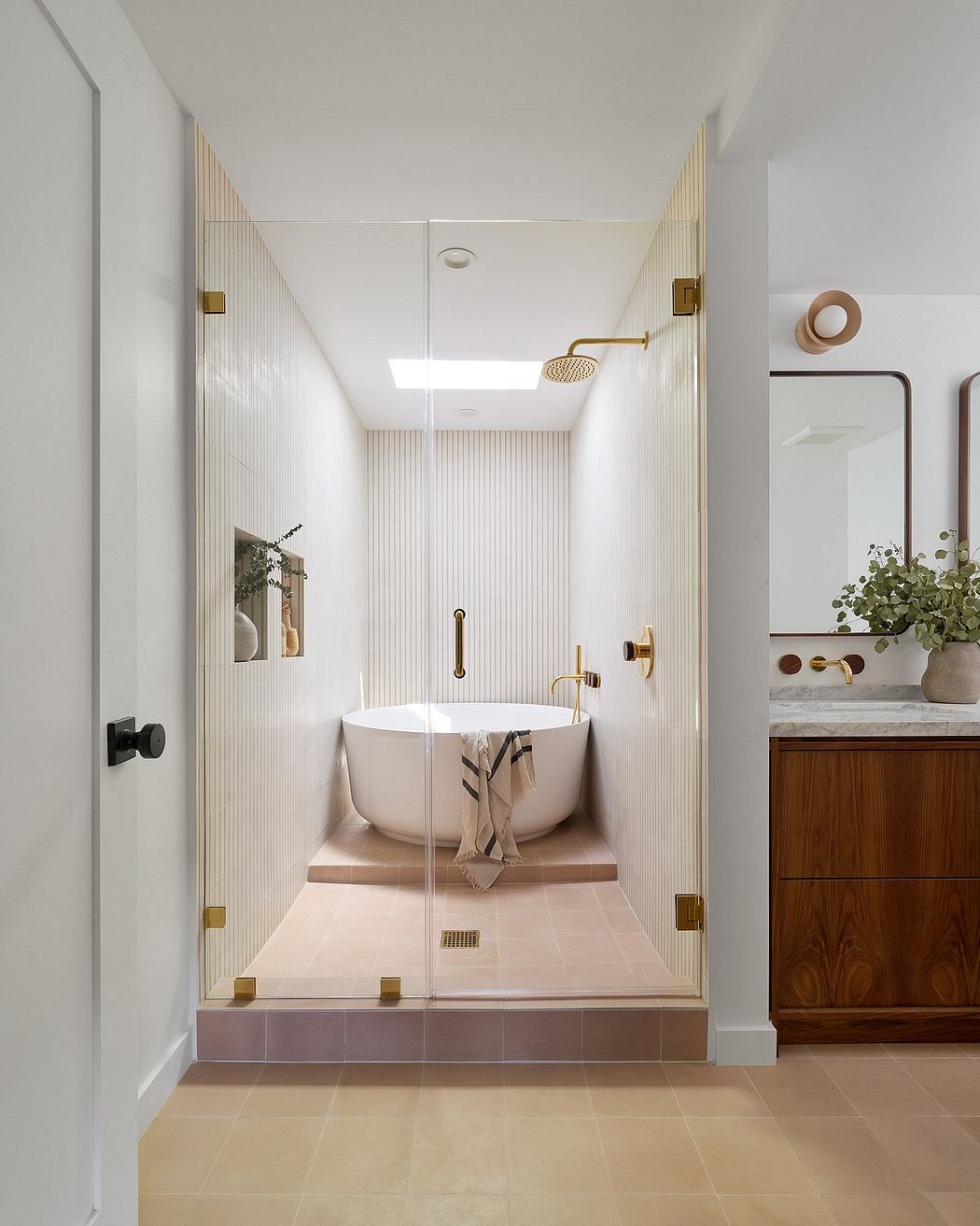A spacious bathroom with a raised tub, glass enclosure, and elegant brass fixtures.