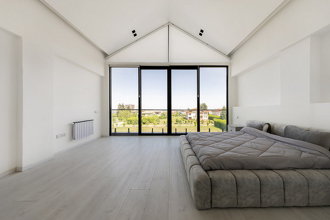 Spacious bedroom with tall windows, vaulted ceiling, and modern hardwood floors.
