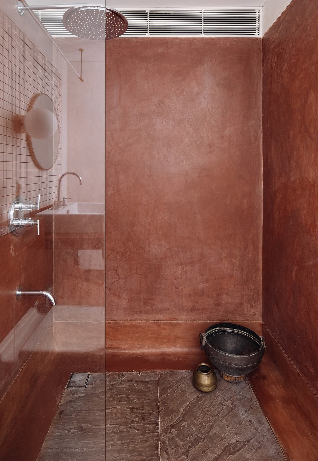A modern bathroom with earthy tones, a large rainfall shower, and rustic decor elements.
