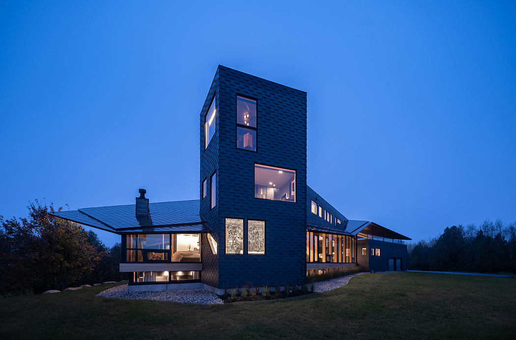 A modern, two-story house with a unique black facade, large windows, and a chimney.