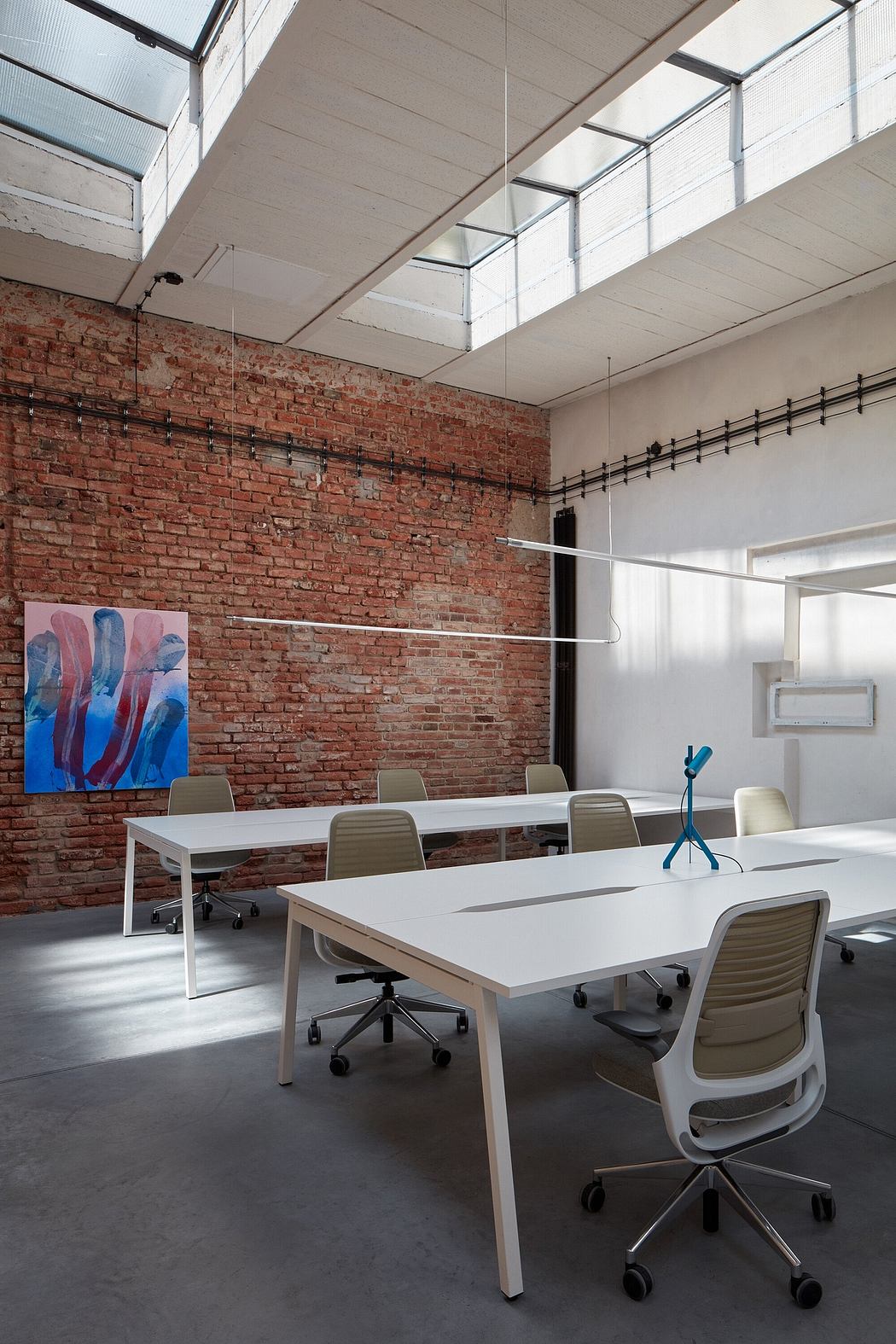 Modern office space with exposed brick walls, large windows, and minimalist furniture.